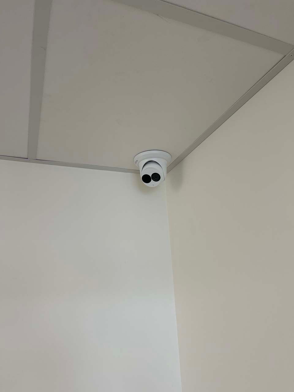A security camera is mounted on the ceiling of a room.