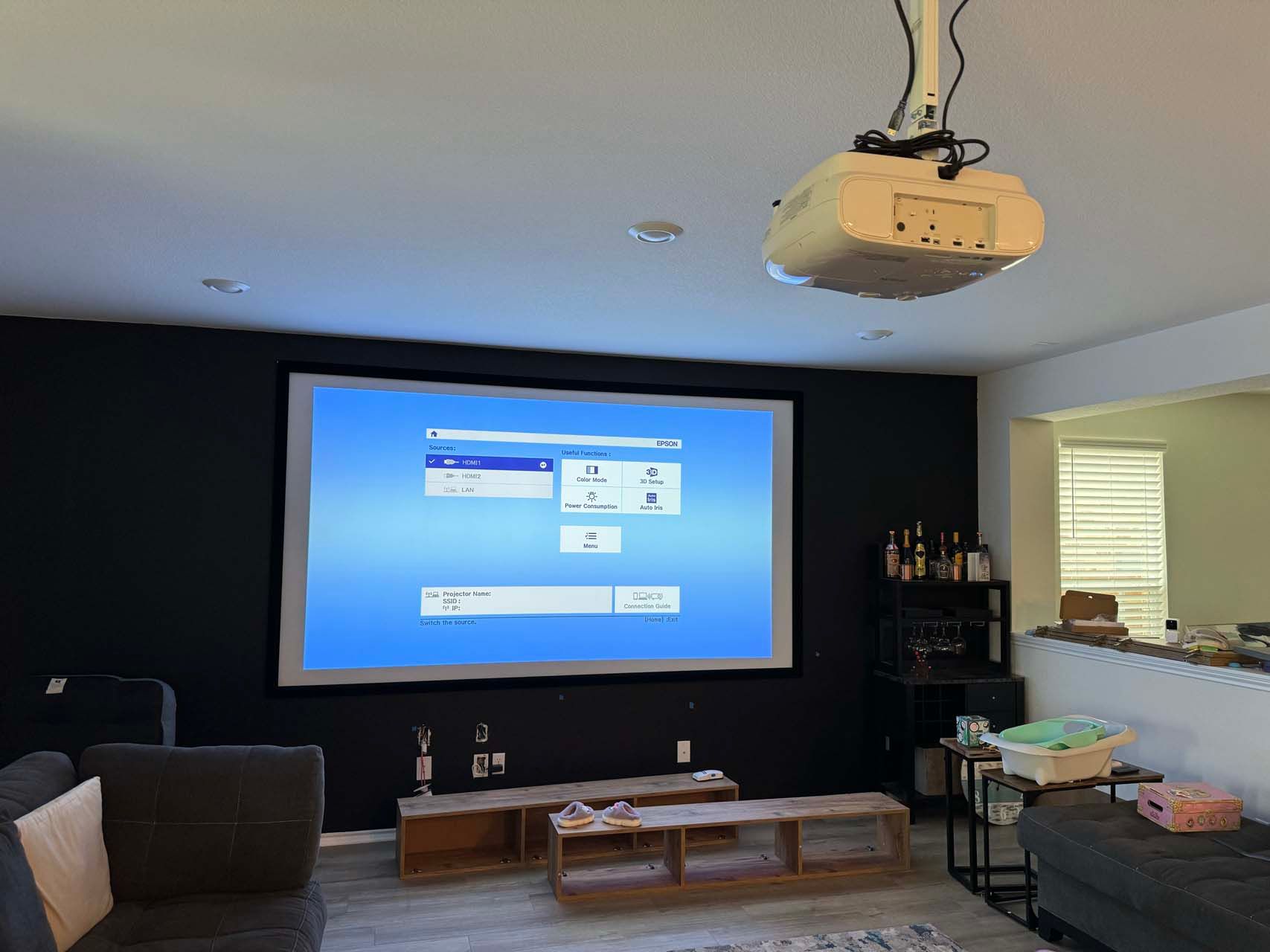 A living room with a projector screen hanging from the ceiling.