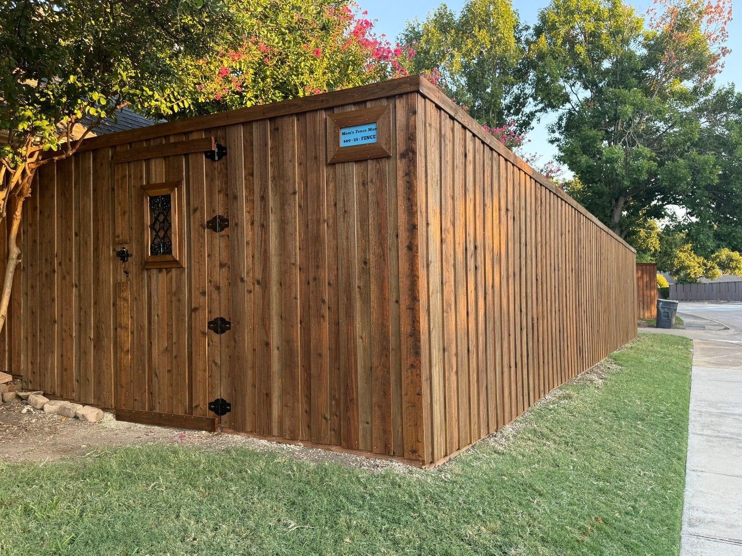 Wooden shed with a slanted roof beside a grassy lawn and trees