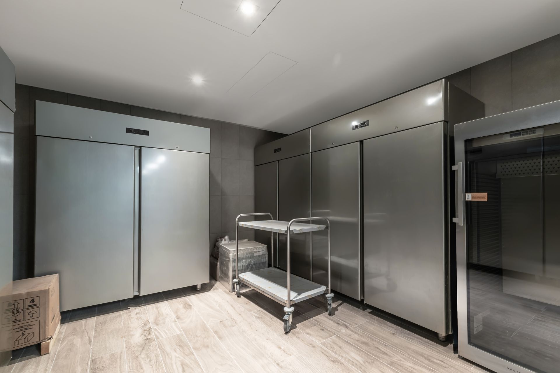 A spacious professional kitchen area features stainless steel refrigerators arranged neatly against 