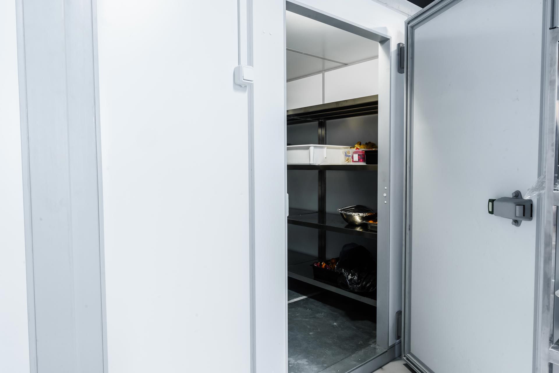 A cool room door is open showing a partial view of metal shelving