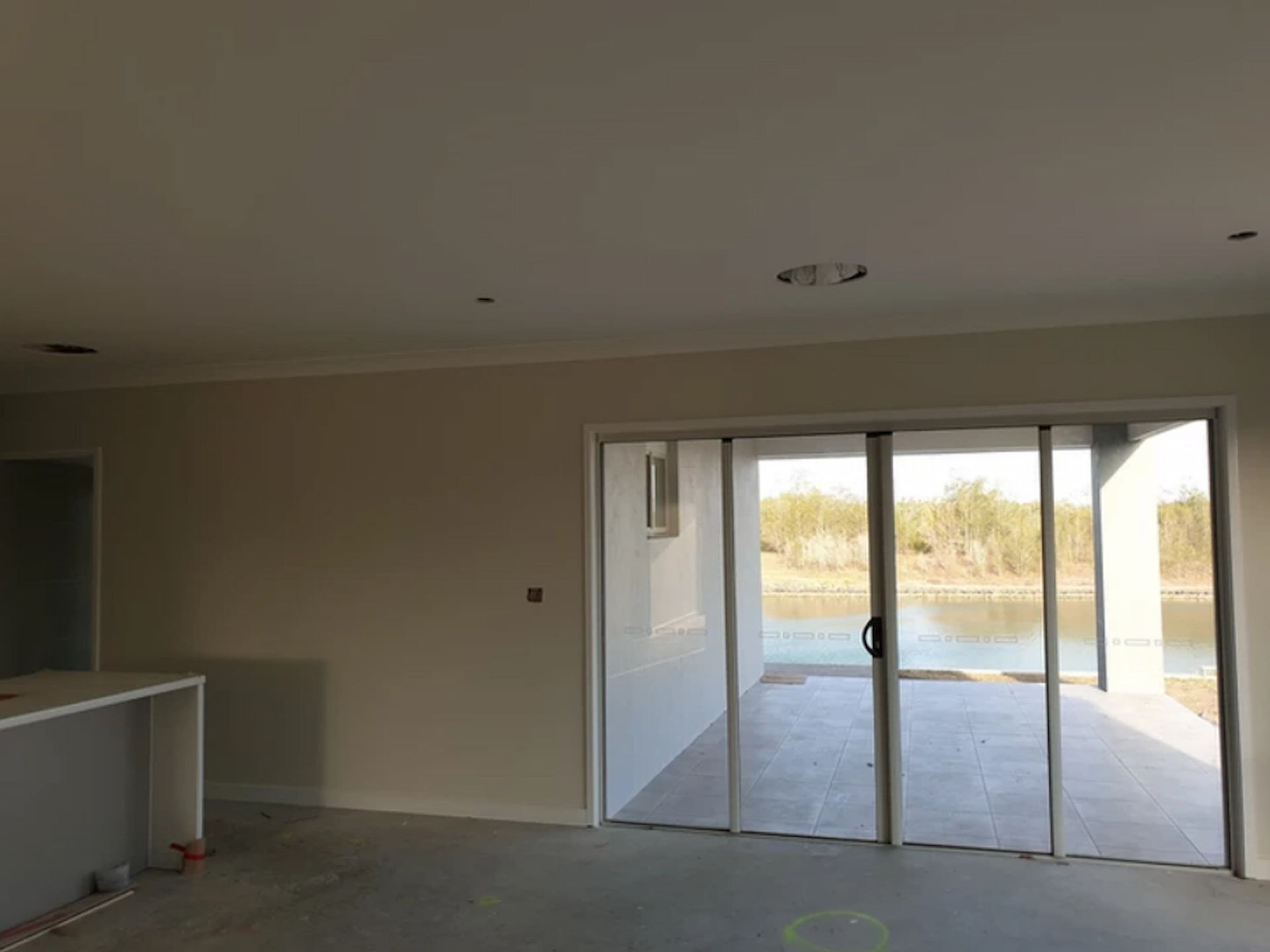 An Empty Room with Sliding Glass Doors Leading to A Lake — A Brush With Colour in Hervey Bay, QLD