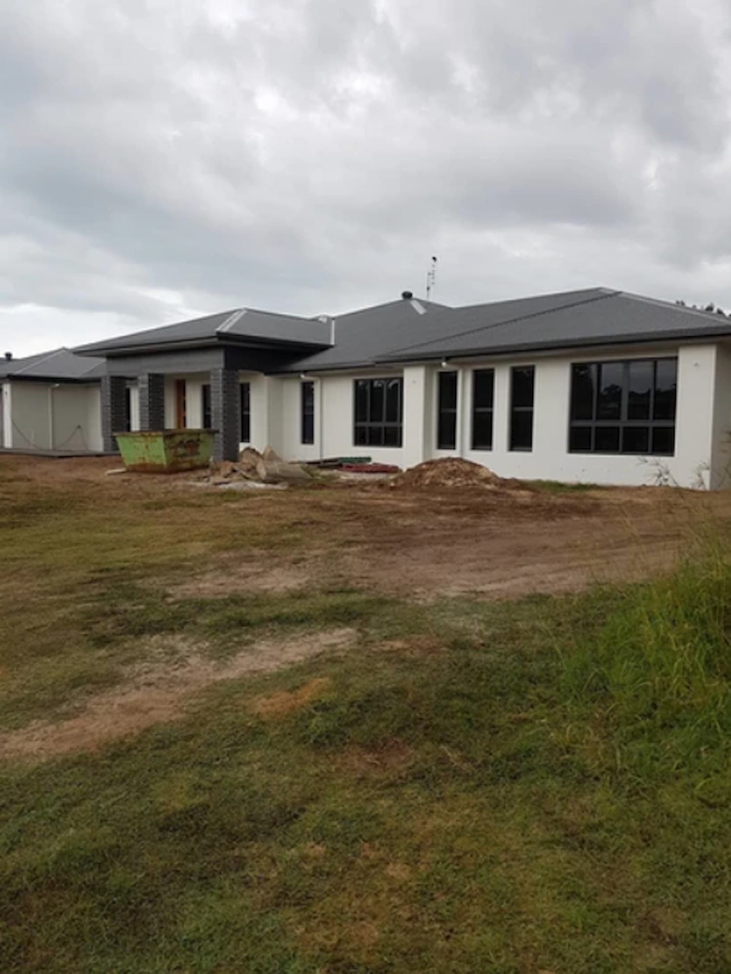 A Large White House with A Gray Roof Is Sitting in The Middle of A Grassy Field — A Brush With Colour in Hervey Bay, QLD