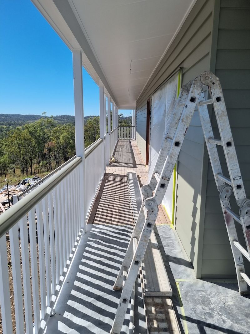 A Man In A White Suit Is Spraying A Roof With Spray Paint — A Brush With Colour in Wondunna, QLD