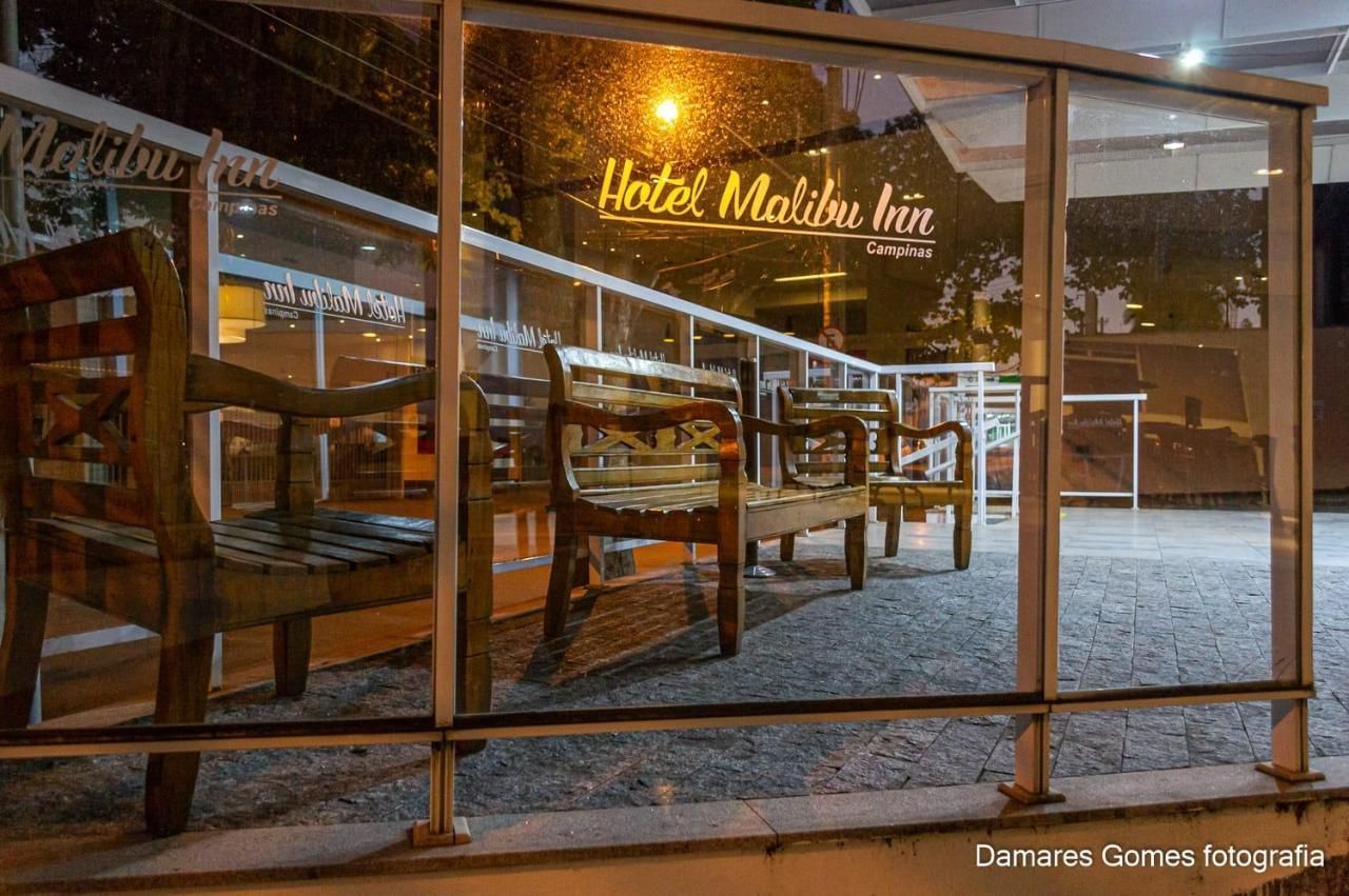 Um banco de madeira está em frente a uma parede de vidro.-hotel-malibu-inn