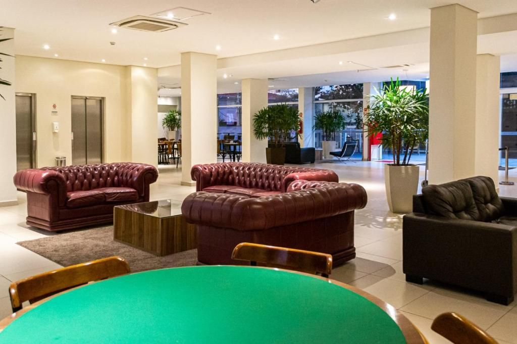 Há uma mesa com uma toalha verde no meio da sala.-hotel-malibu-inn