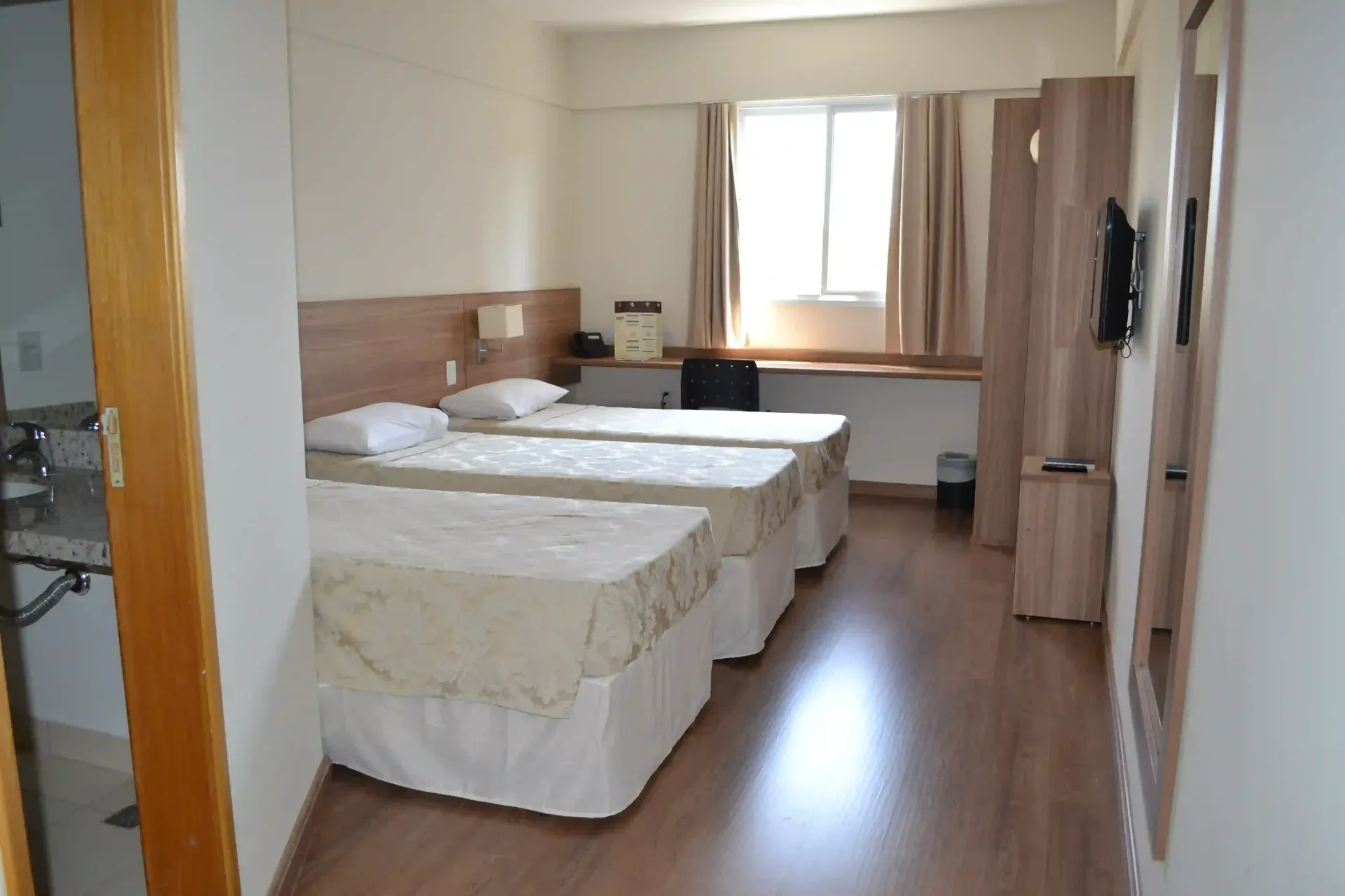 Um quarto de hotel com duas camas, uma pia e uma televisão.-hotel-malibu-inn