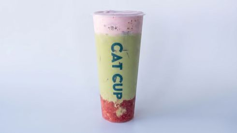 Tall pastel drink cup with a pink lid and red strawberry-like base on a light background