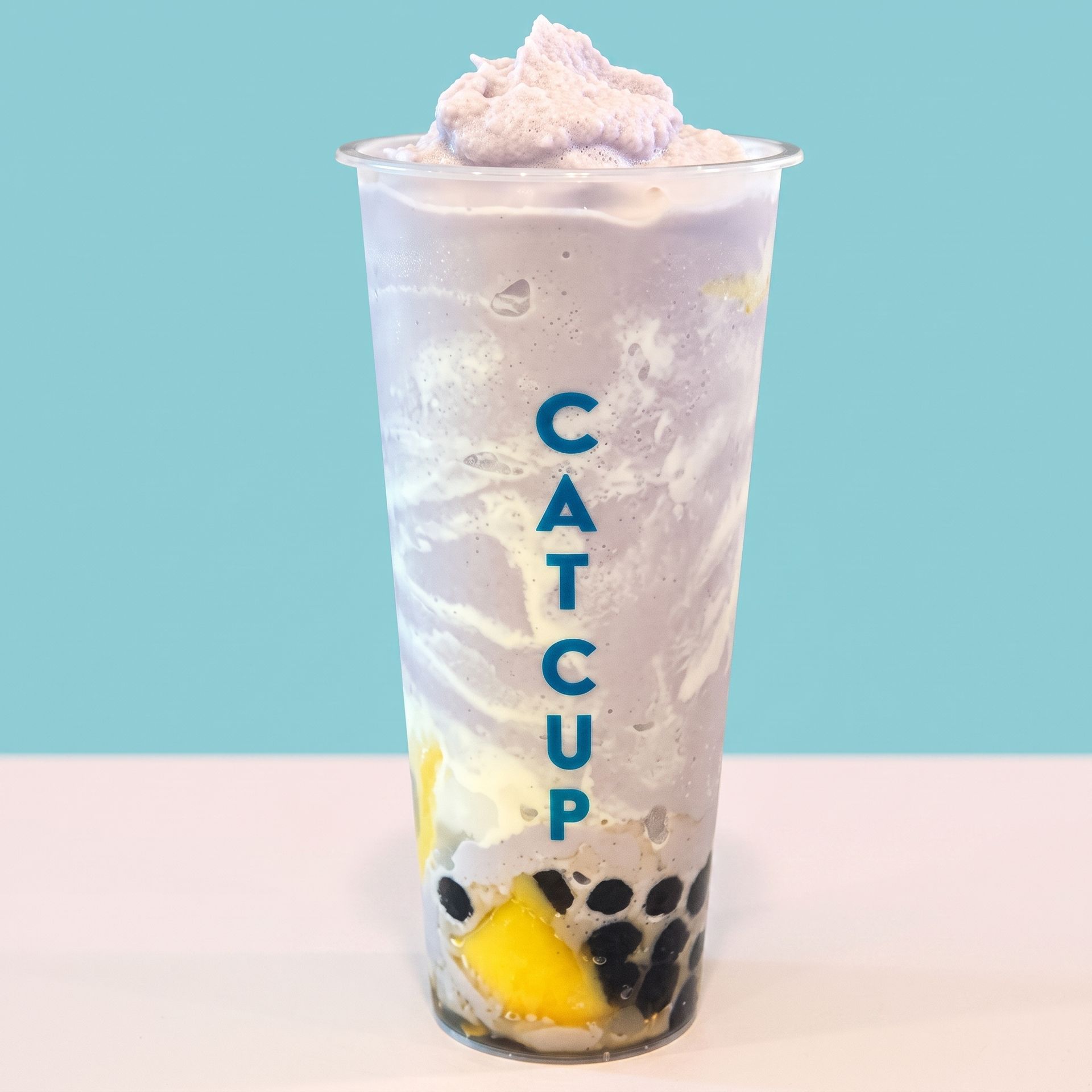 Pastel bubble tea in a clear cup with “CAT CUP” text and yellow lemon garnish on a light blue background