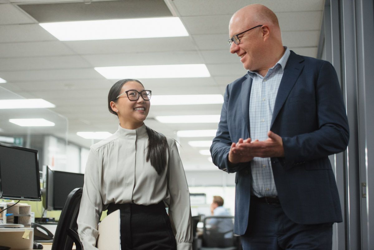 Office manager talking with a staff member walking down the office hallway.