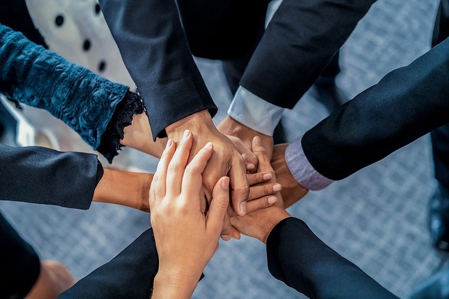 Many hands coming together into a pile depicting trust, and togetherness.