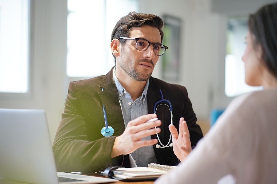 Modern young doctor speaking to patient in office