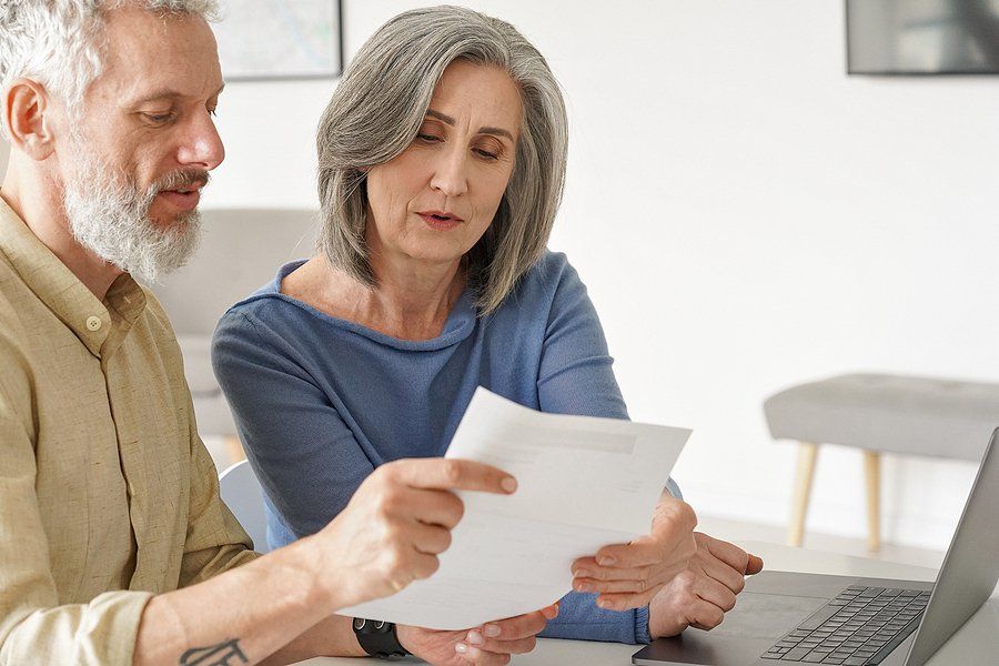Mature couple reviewing paperwork next to a computer.