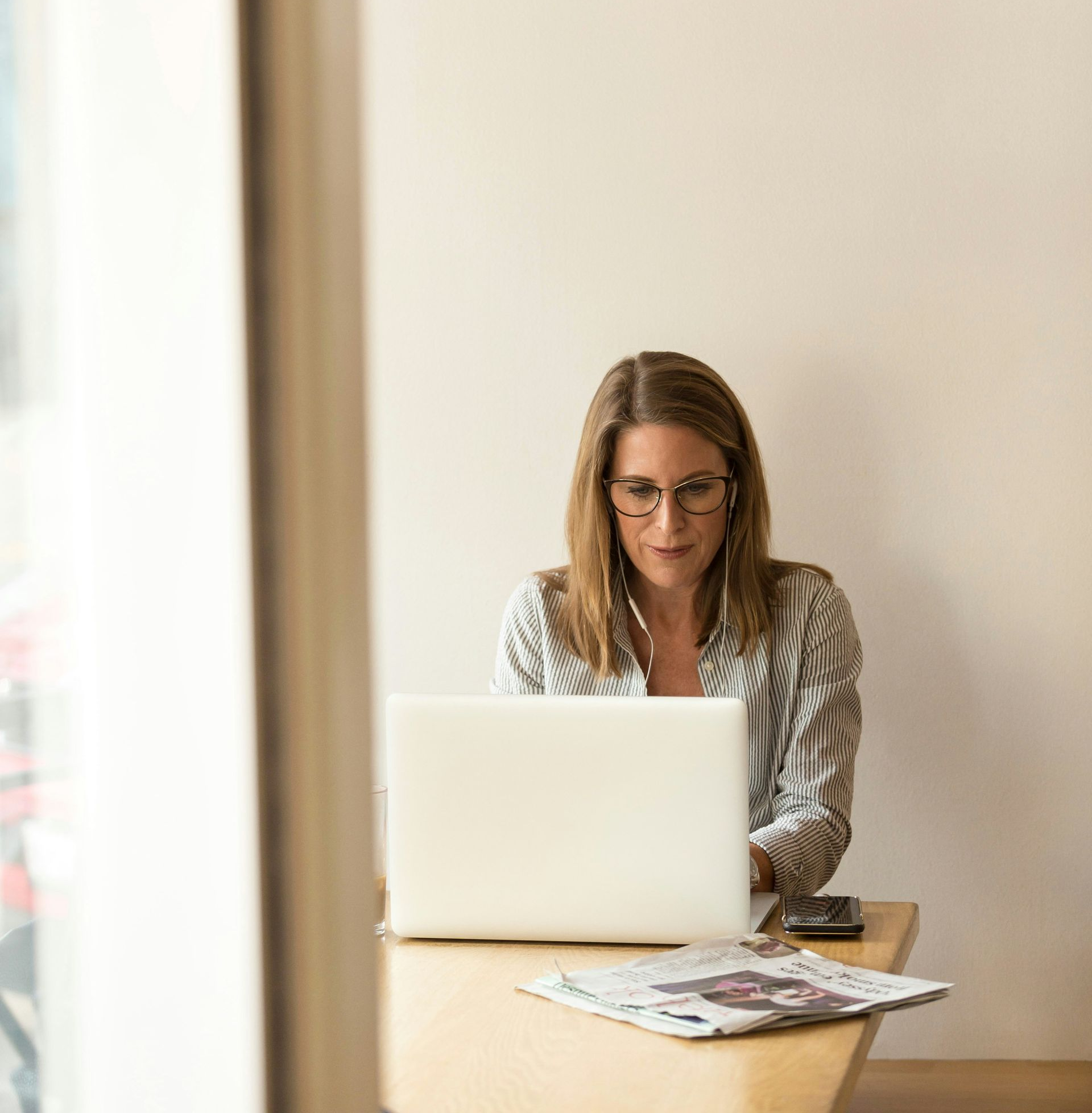 woman in shirt sitting at desk on laptop looking at tax