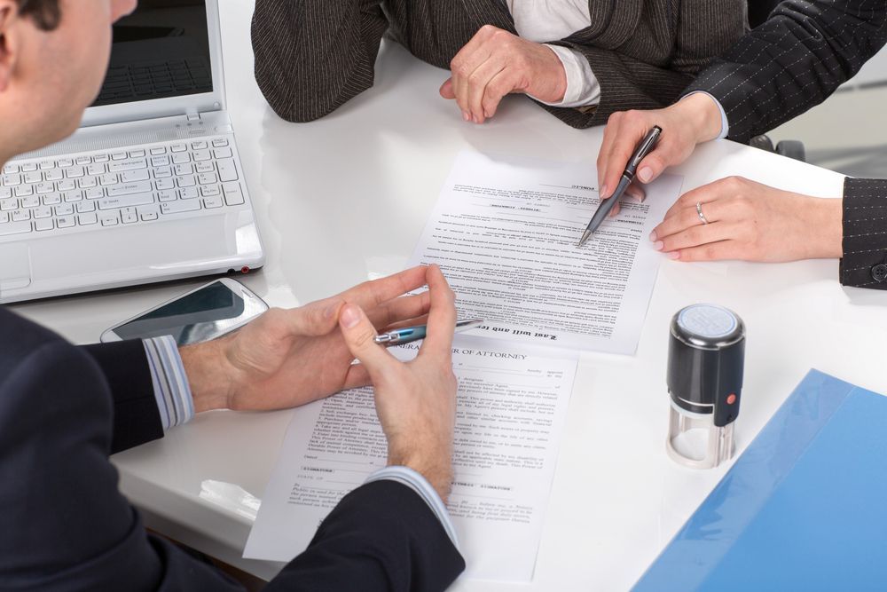 People Reviewing Documents With Attorney at a Table — Hannaway Lawyers in Port Macquarie, NSW