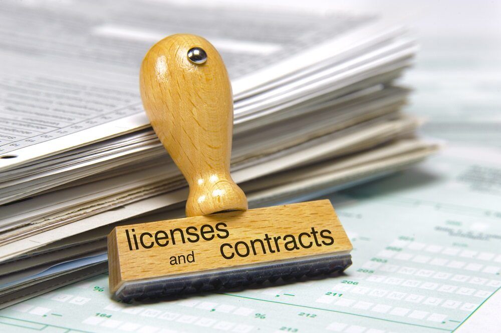 Wooden Stamp With Text Licenses and Contracts on Stack of Papers — Hannaway Lawyers in Kempsey, NSW