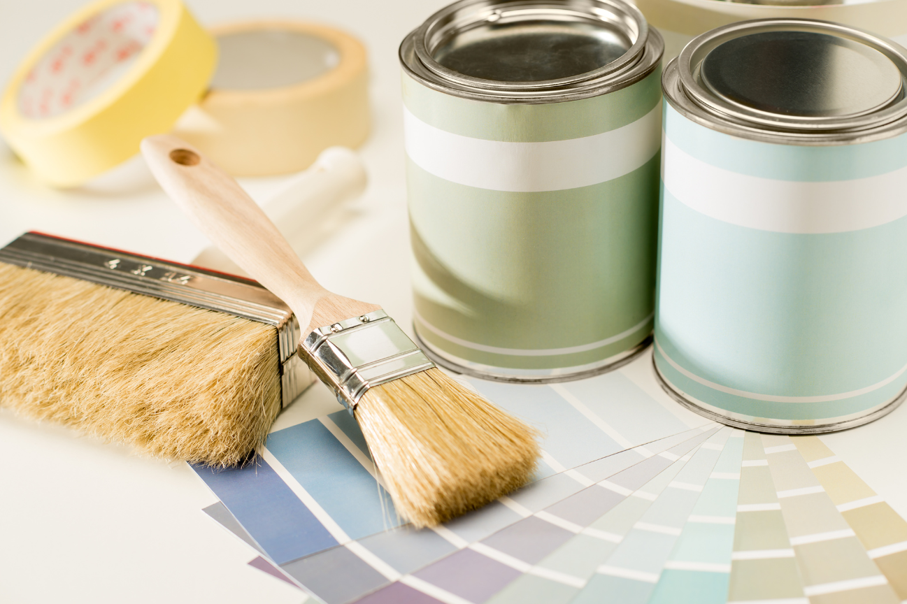 Three cans of paint and a brush on top of a color chart