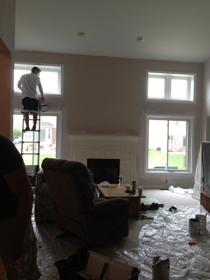 A man is standing on a ladder in a living room