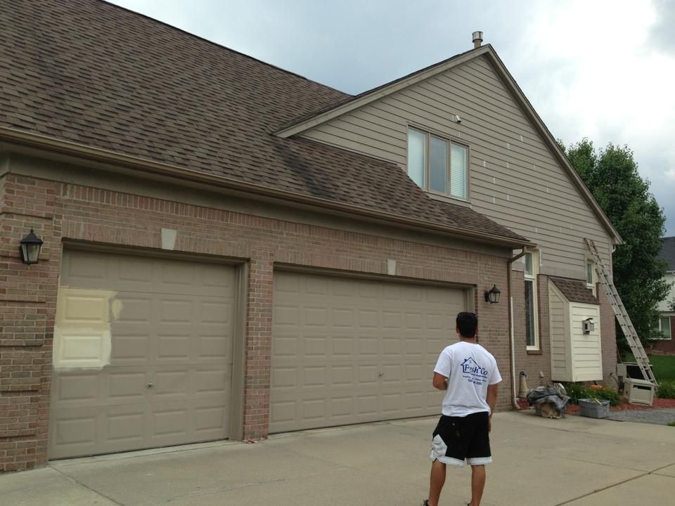 A man is standing in front of a house with three garage doors.