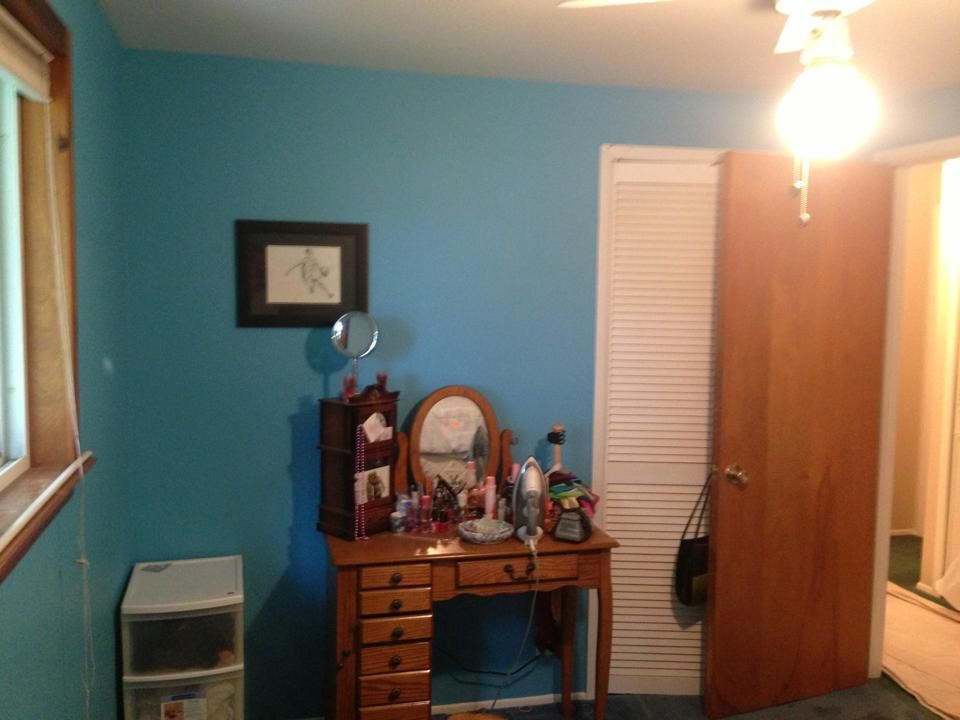 A bedroom with blue walls and a wooden desk