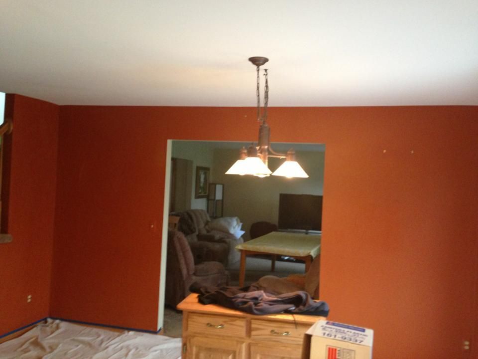A living room with red walls and a chandelier hanging from the ceiling