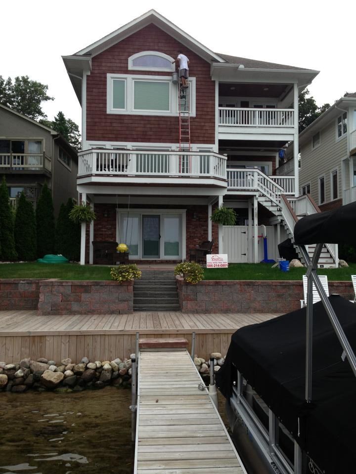 A boat is docked in front of a large brick house