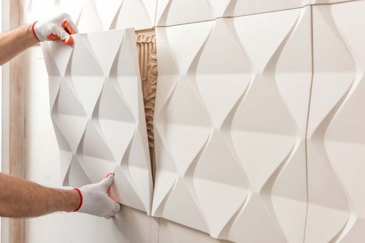 A worker is attaching the gypsum tile to the wall