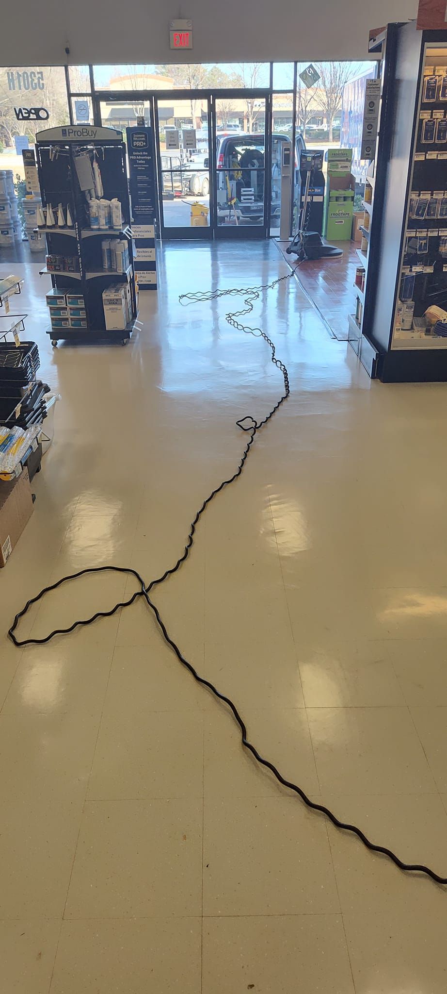 A long black cord is laying on the floor in a store.