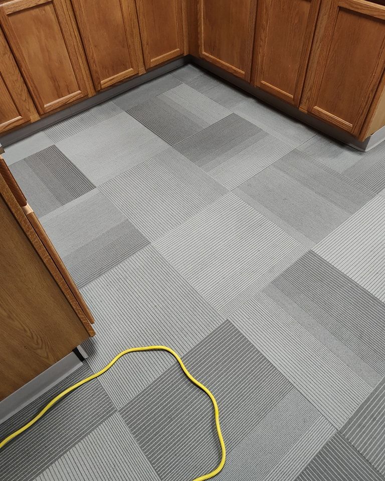 A yellow cord is laying on a tiled floor in a kitchen.