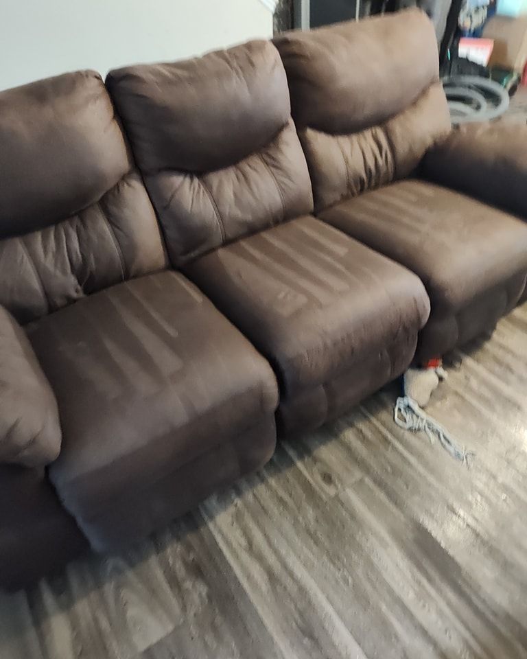 A brown leather couch is sitting on a wooden floor