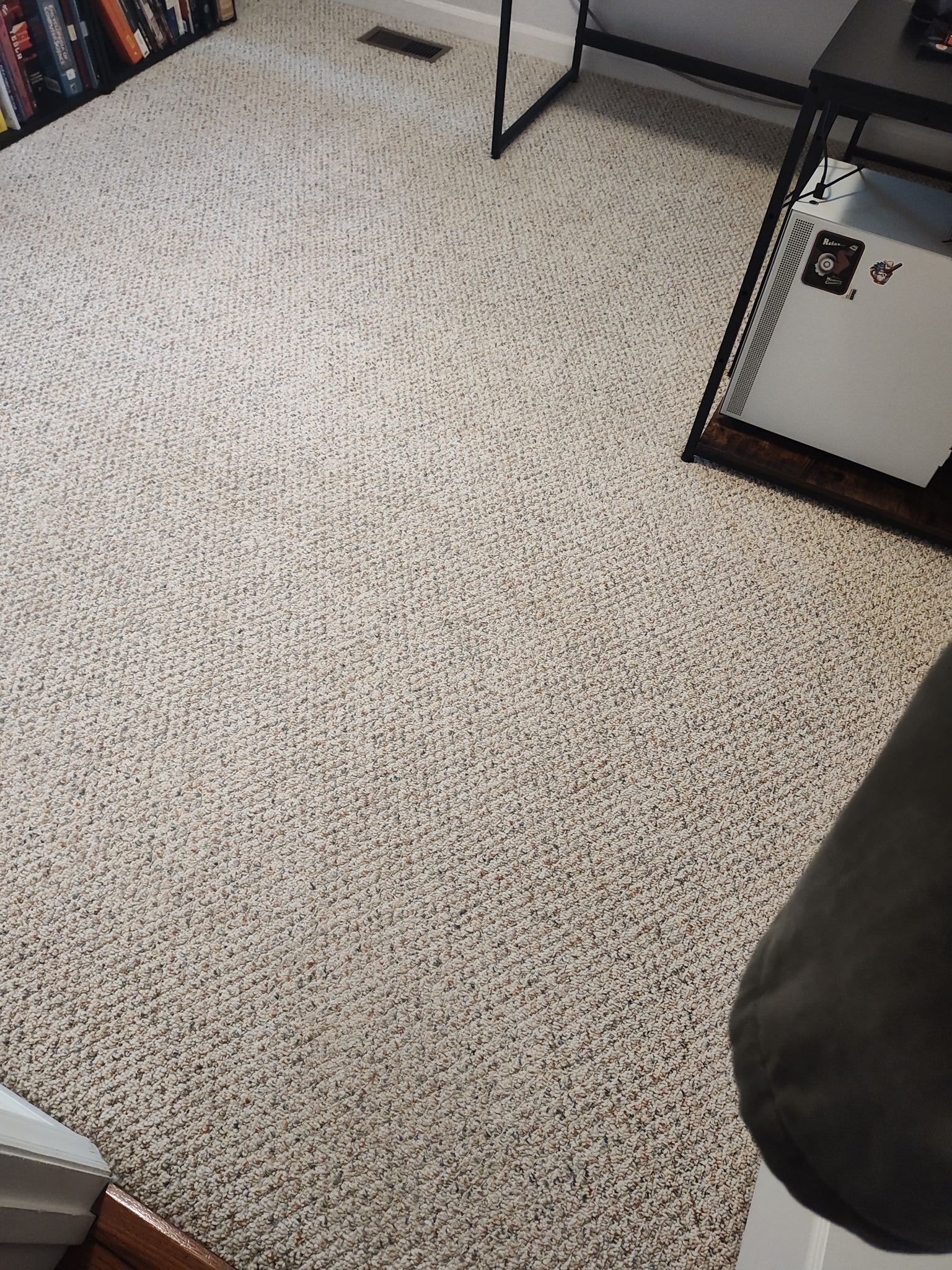 A carpeted floor in a living room with a projector on it.