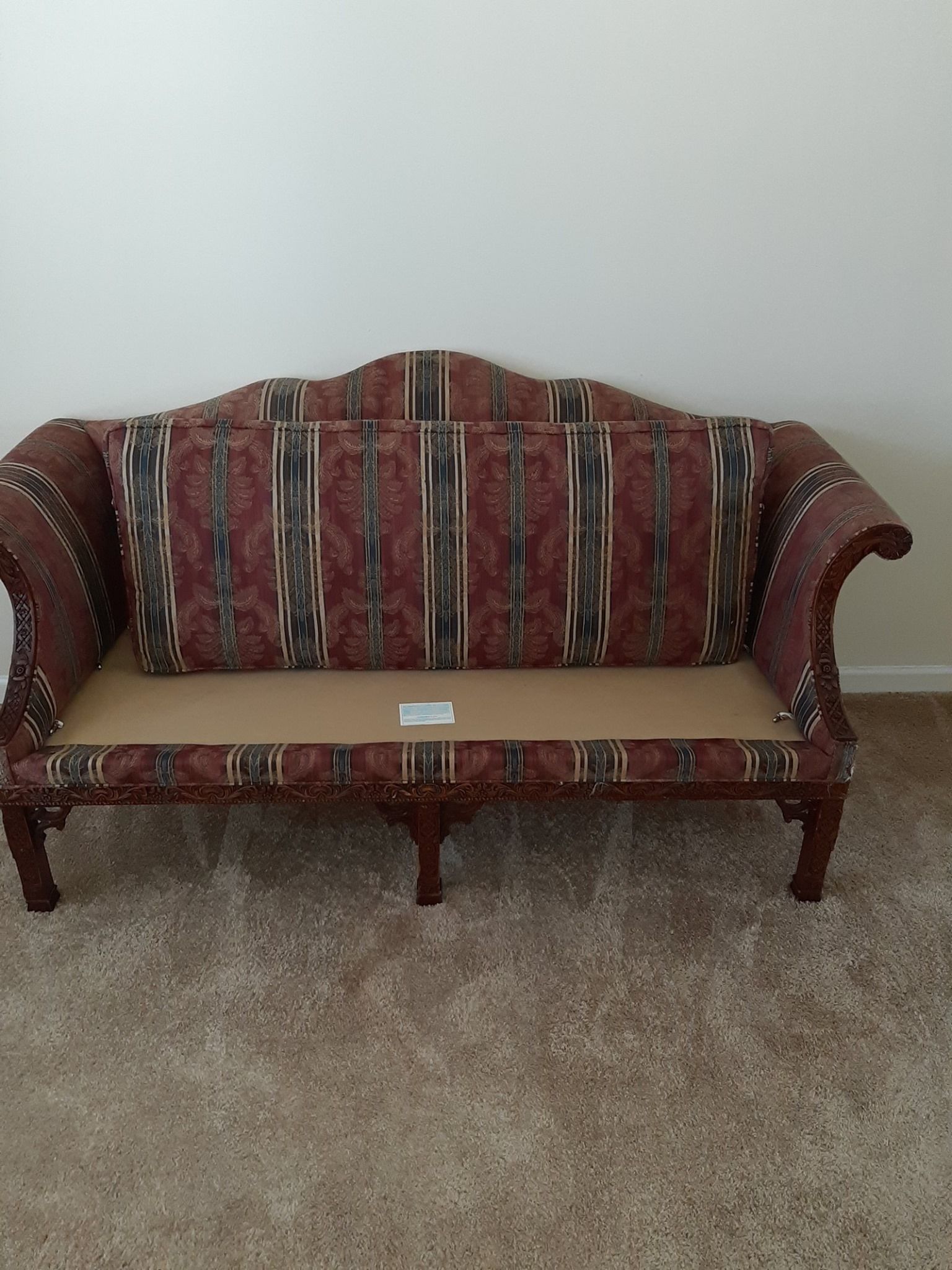 A red couch is sitting on a carpeted floor in a living room.