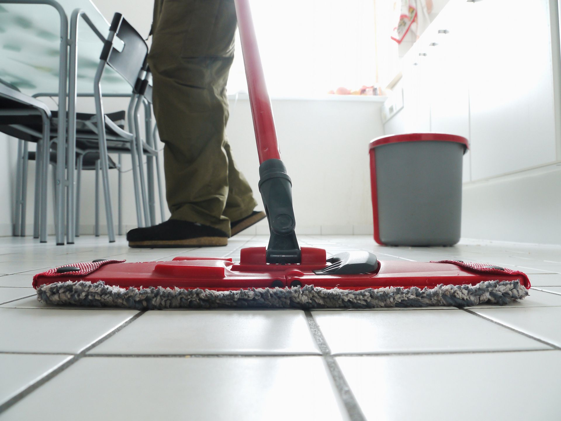 A person is mopping the floor with a red mop