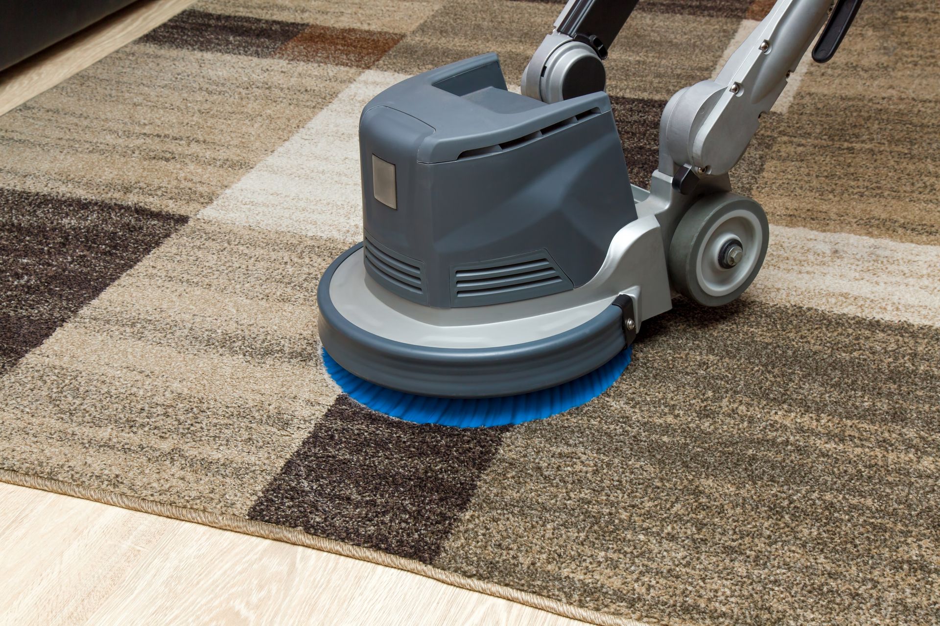 A machine is cleaning a rug on a wooden floor