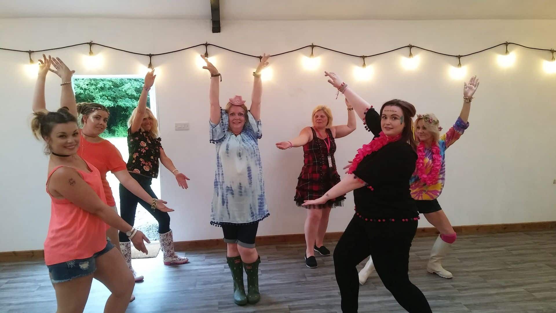 A group of women are dancing in a room with their arms in the air.