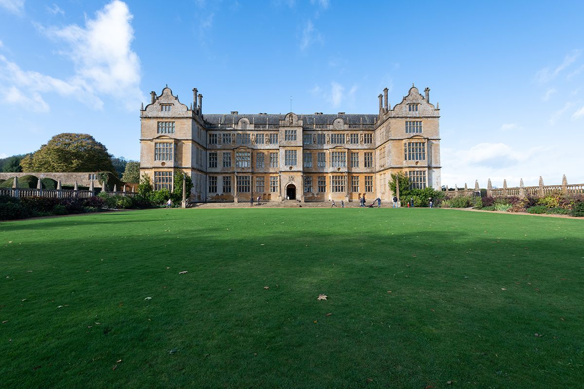 A large building with a lush green field in front of it.