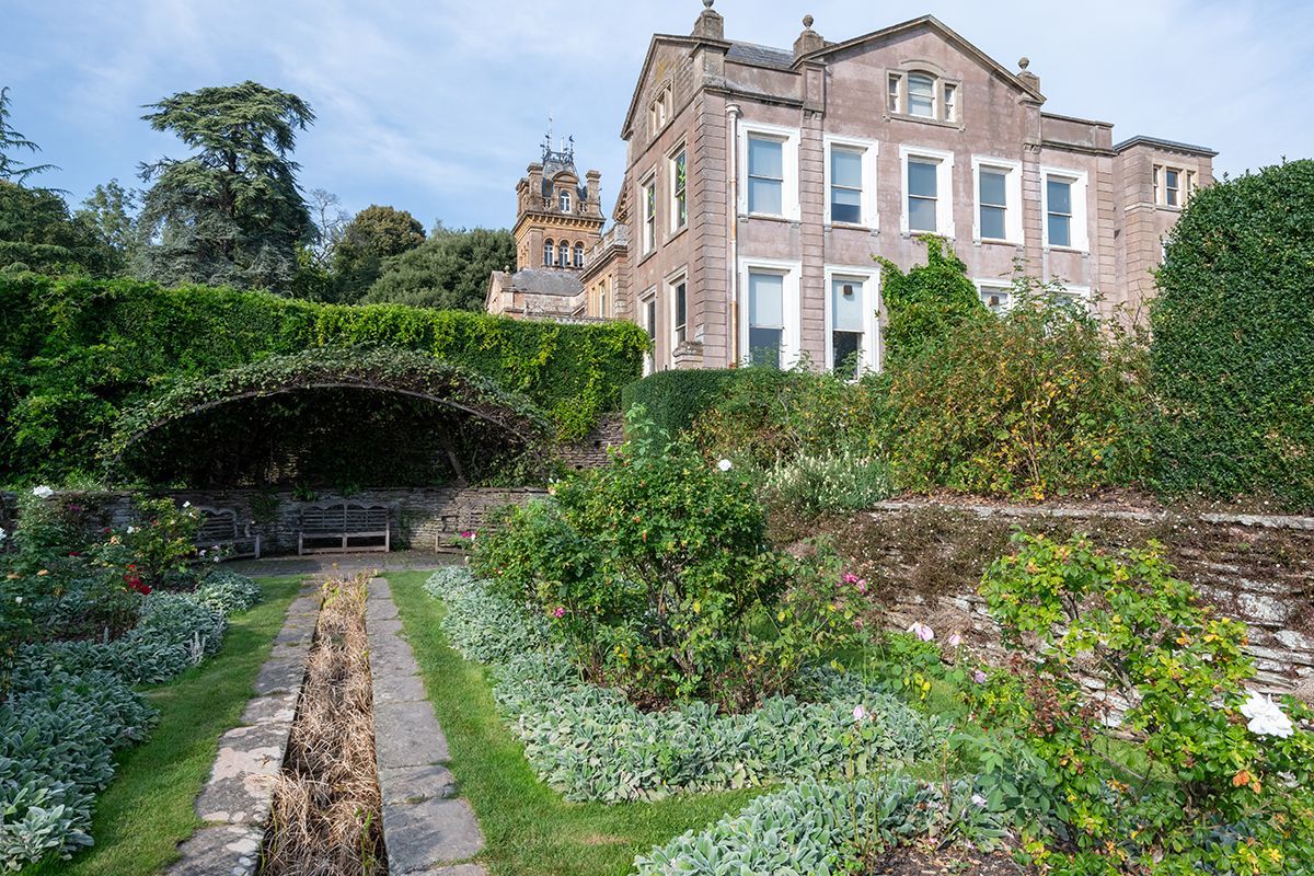 A large house is surrounded by a lush green garden.