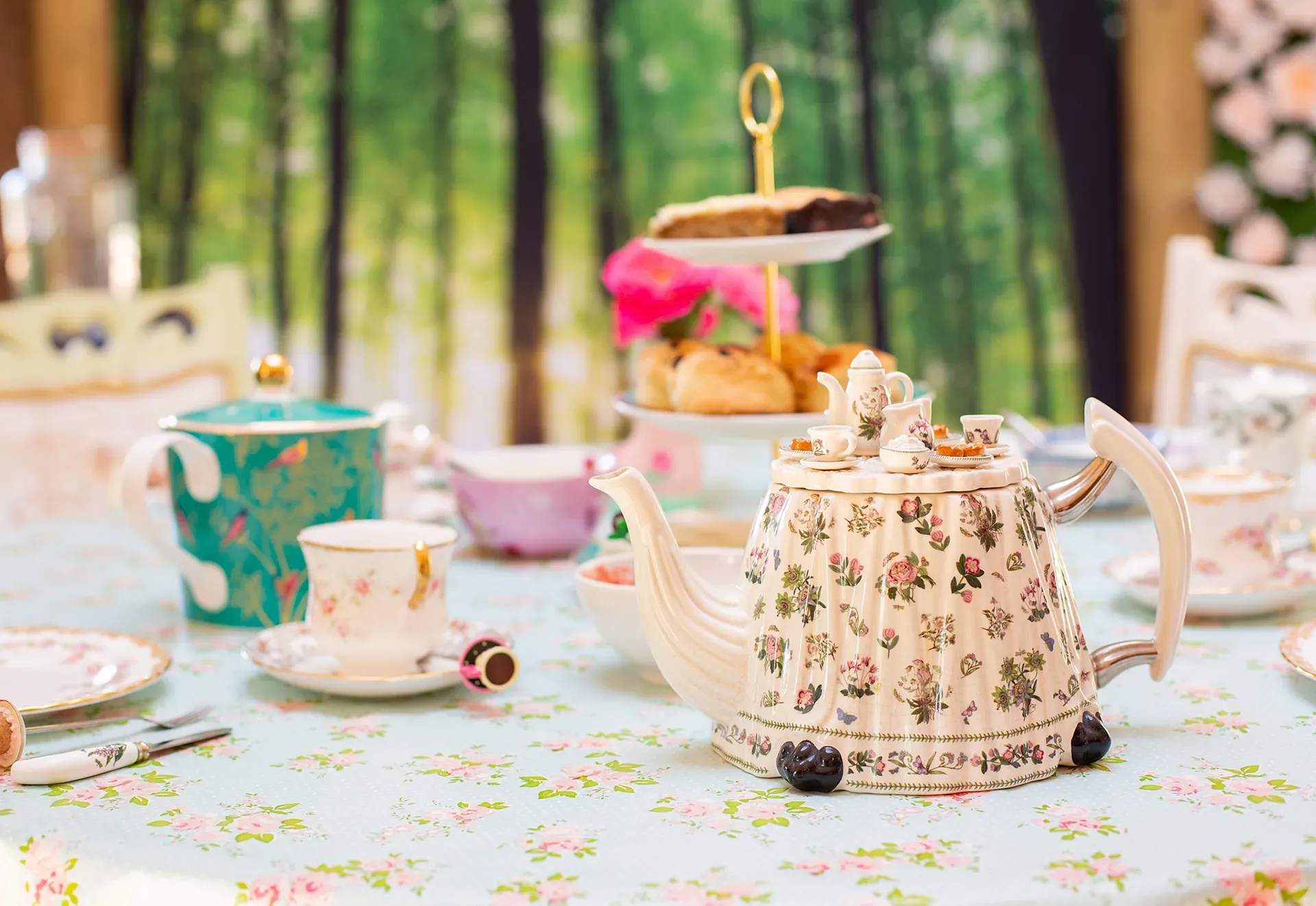 A table set for a tea party with a teapot , cups , saucers and a cake stand.