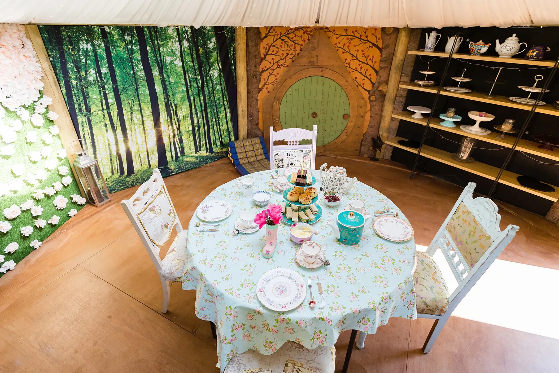 A round table with plates , cups and saucers on it in a room.