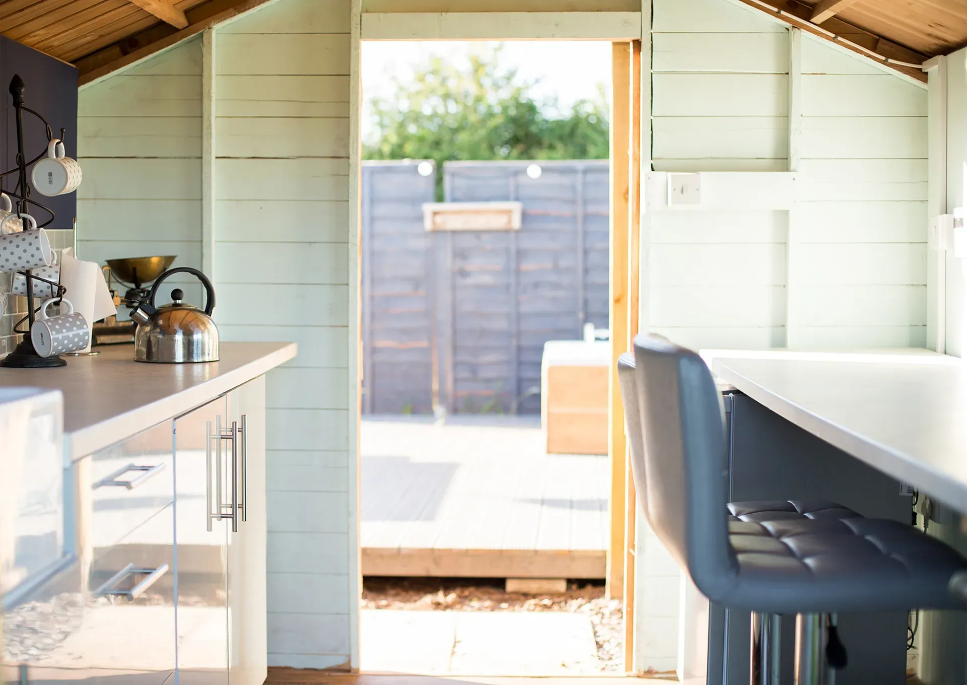 A kitchen in a shed with a view of a fence.