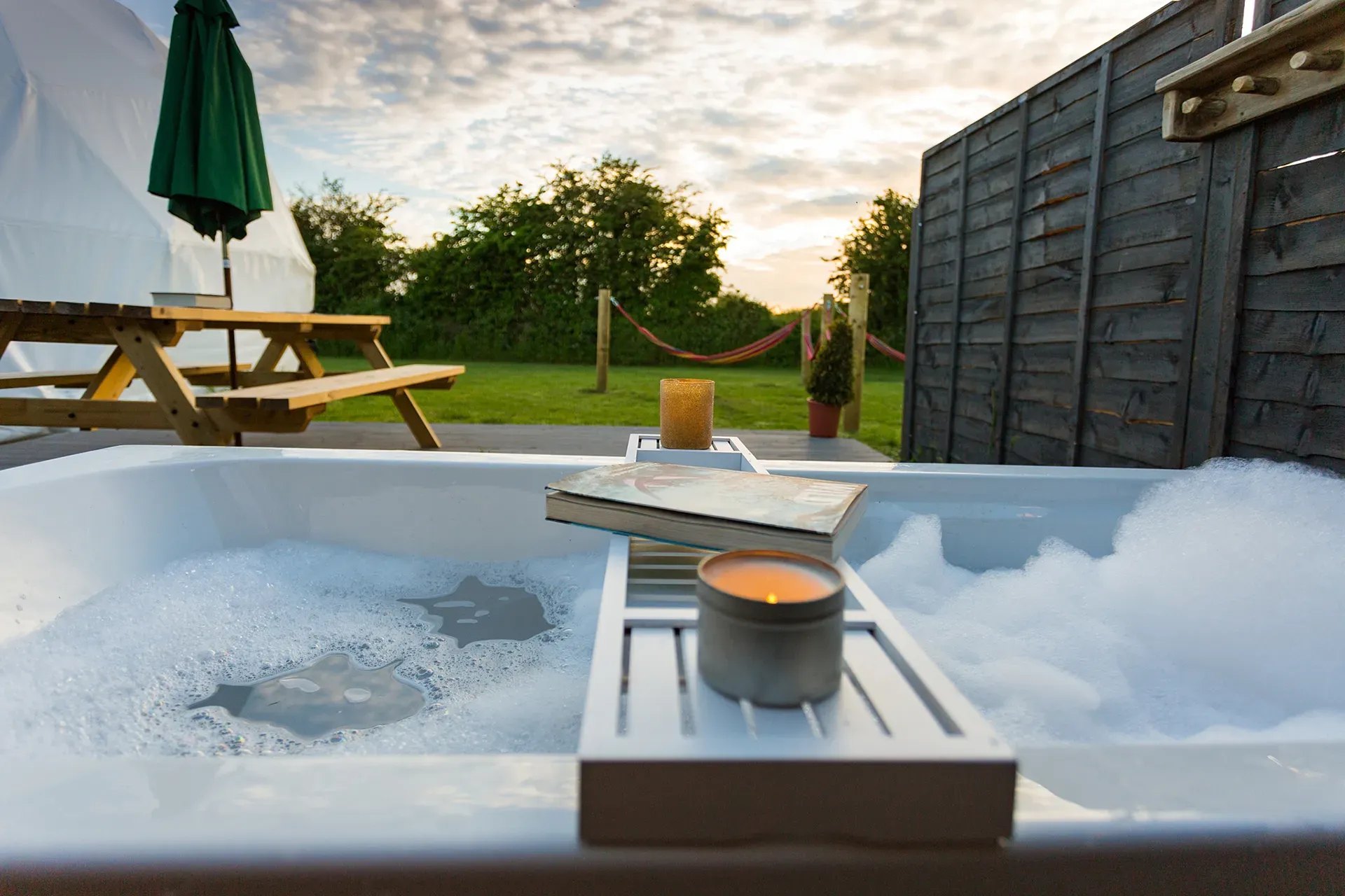 A hot tub with a book and a candle on a tray.