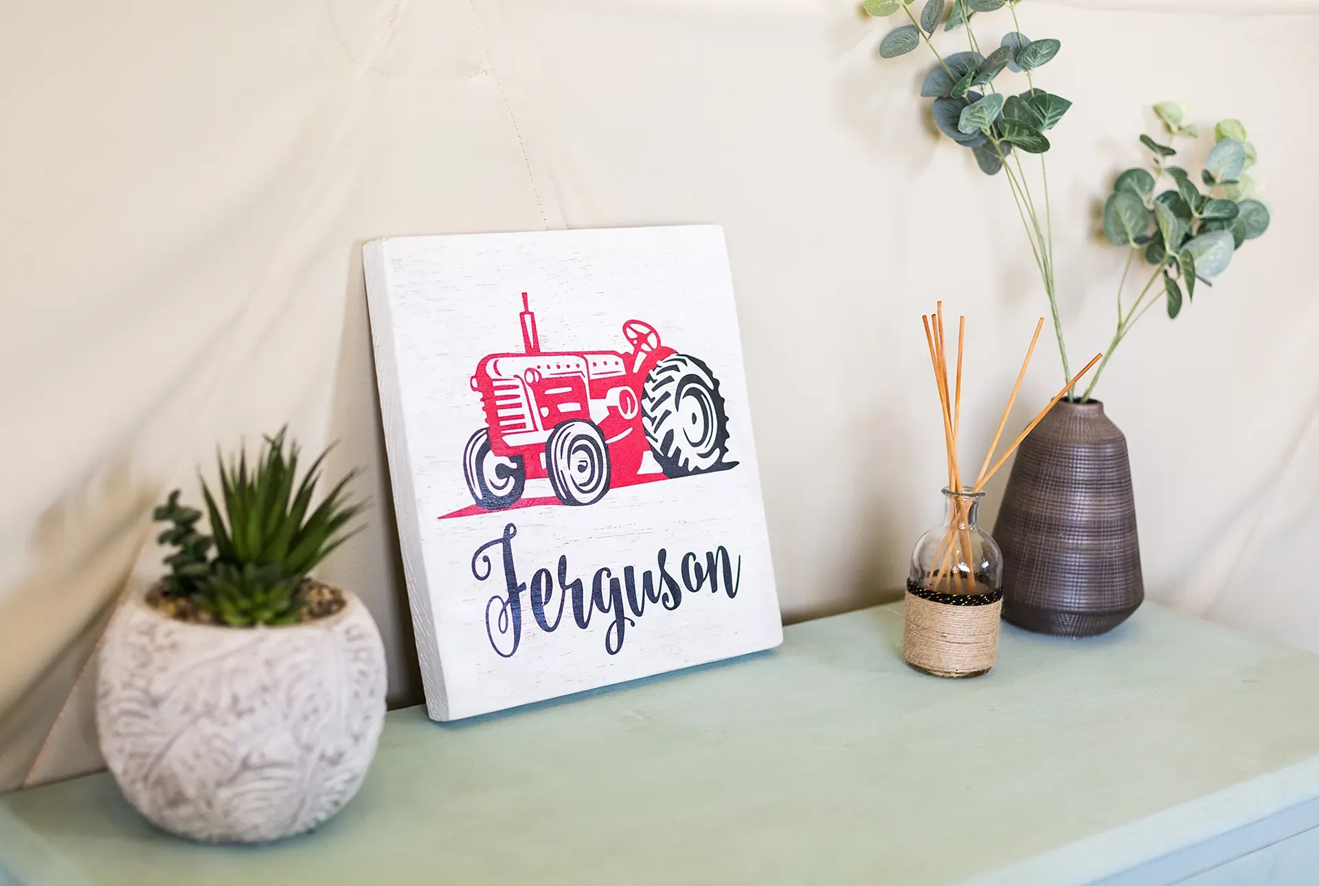 A painting of a red tractor with the name ferguson on it is sitting on a table.
