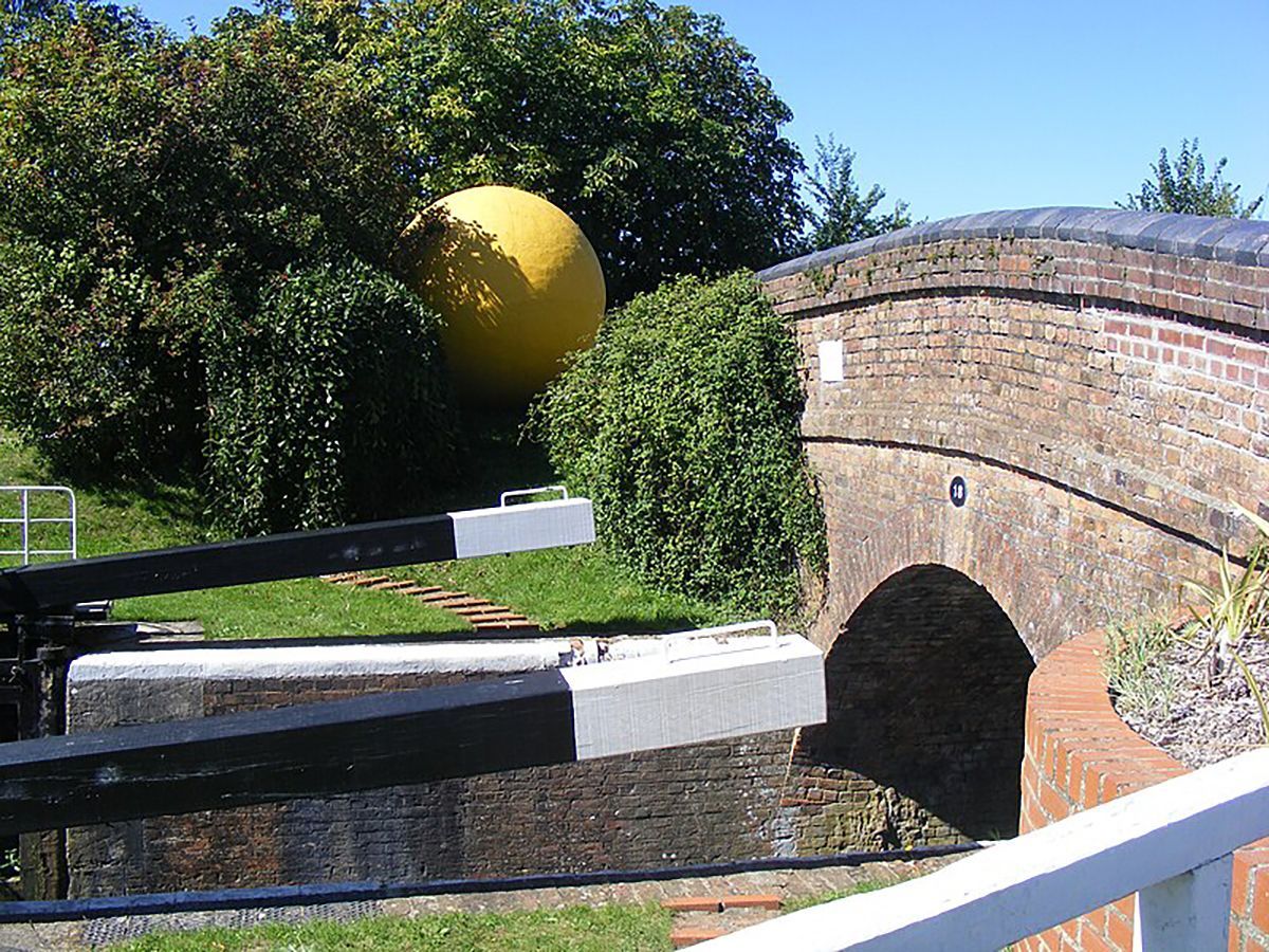 A large yellow ball is sitting on top of a brick bridge
