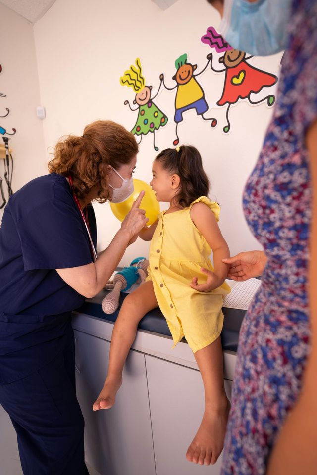 A doctor is talking to a little girl on a medical table.