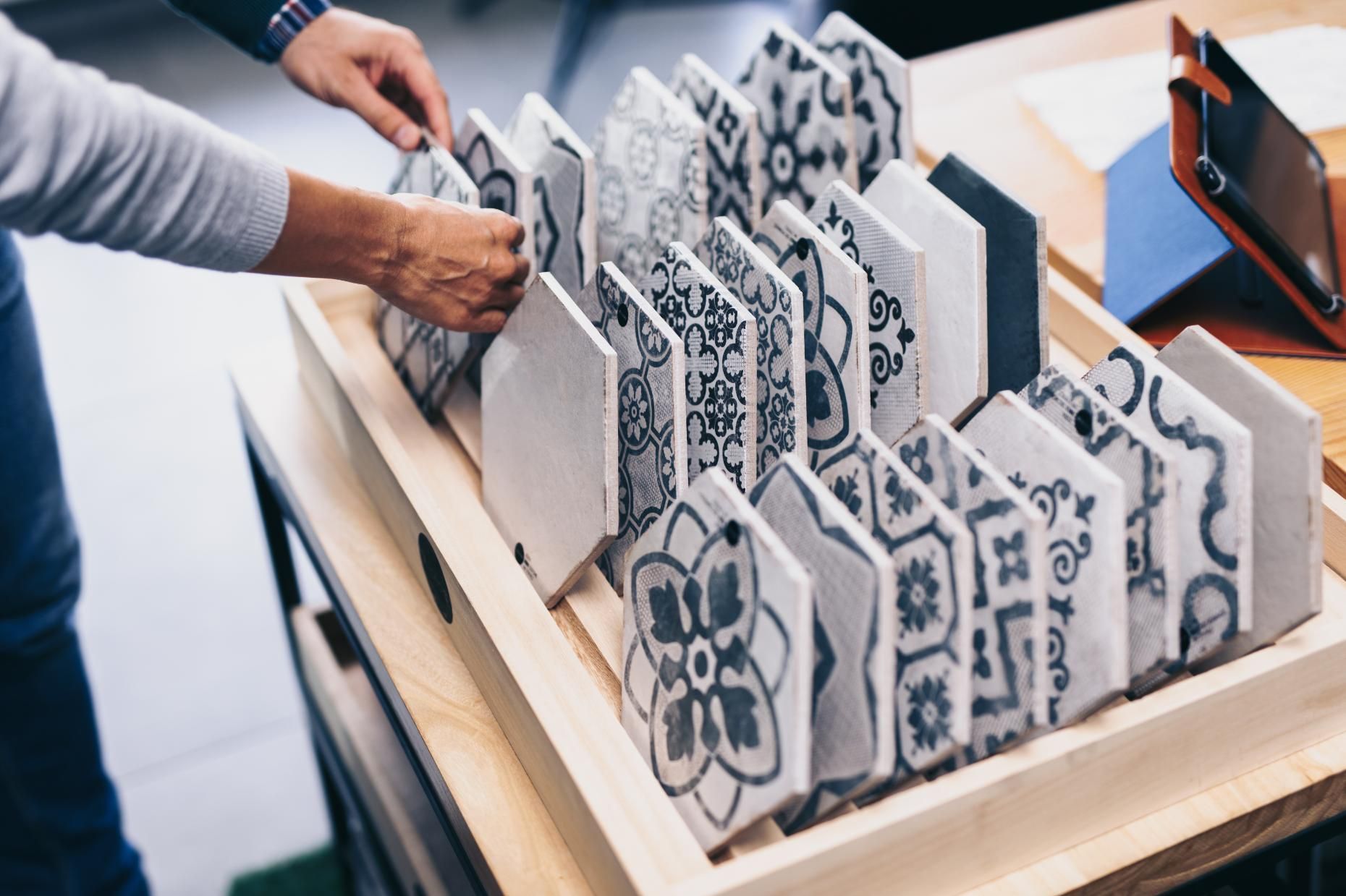Hands arranging patterned hexagonal cards in a wooden display tray