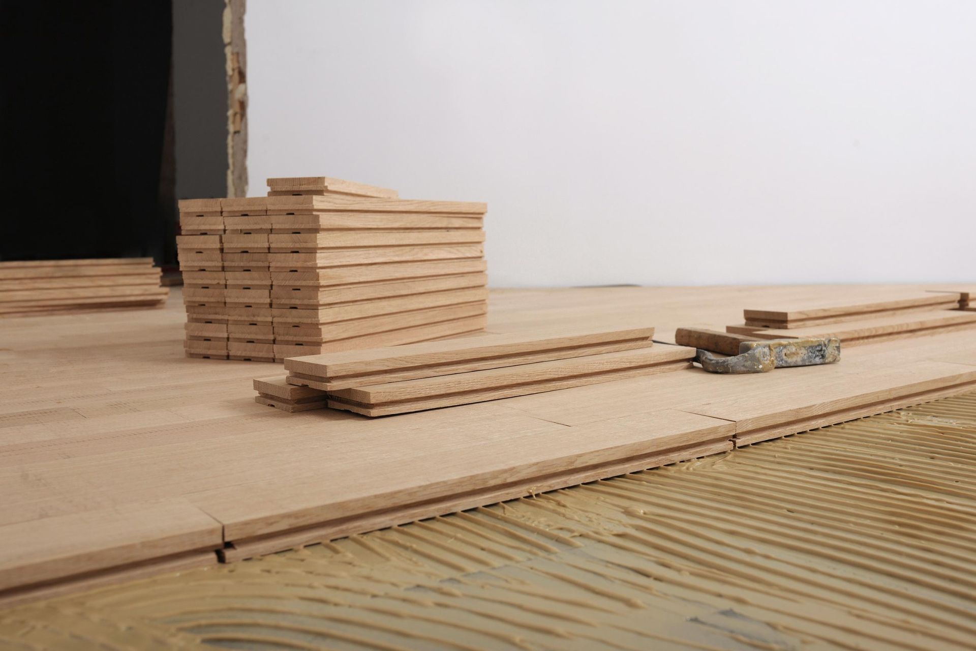 Stacked wood planks on a wooden floor with a black opening in the background