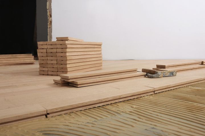 Stacked wood planks on a wooden floor with a black opening in the background