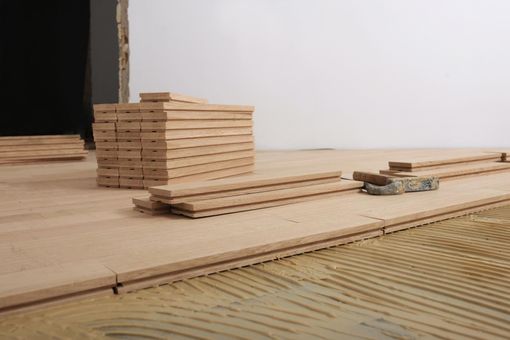Stacked wood planks on a wooden floor with a black opening in the background