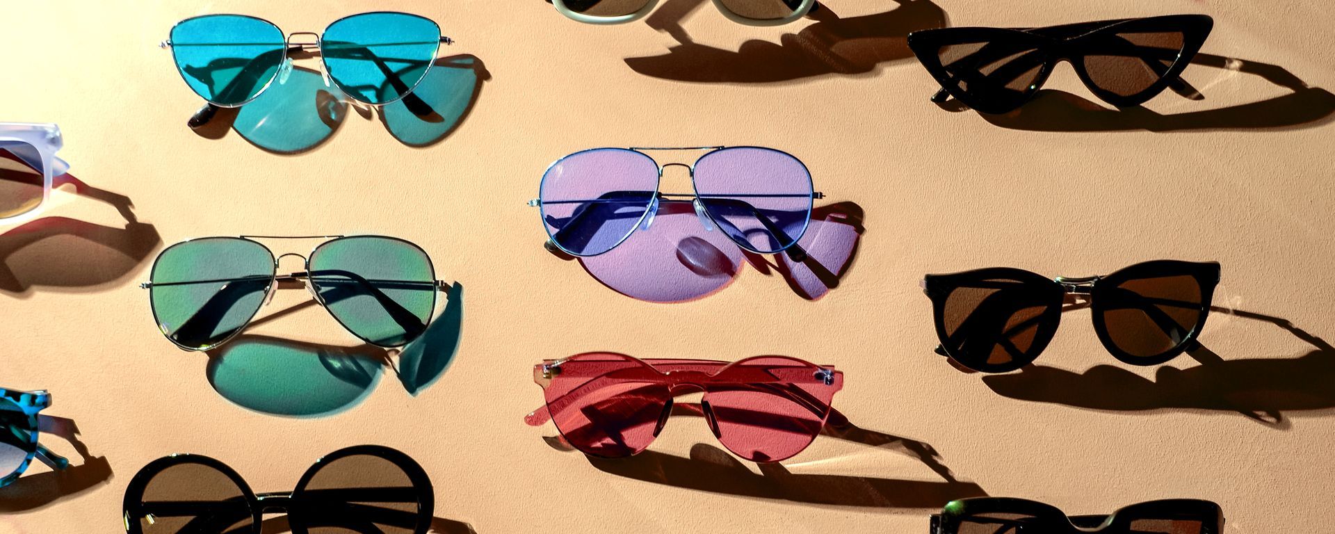 Assorted sunglasses displayed on a colorful background in a variety of styles.