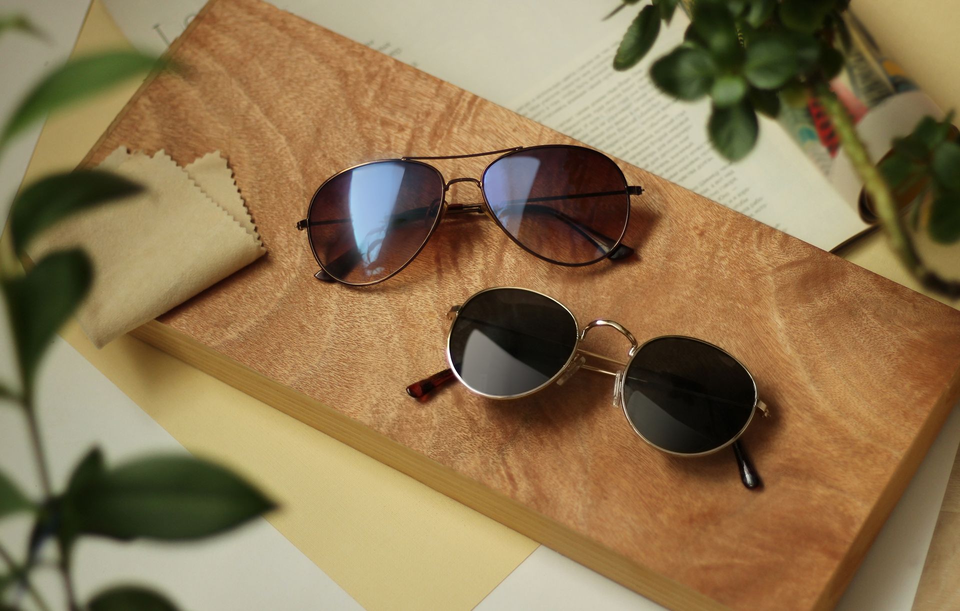 Two pairs of sunglasses resting on a stack of paper with a minimalist display.